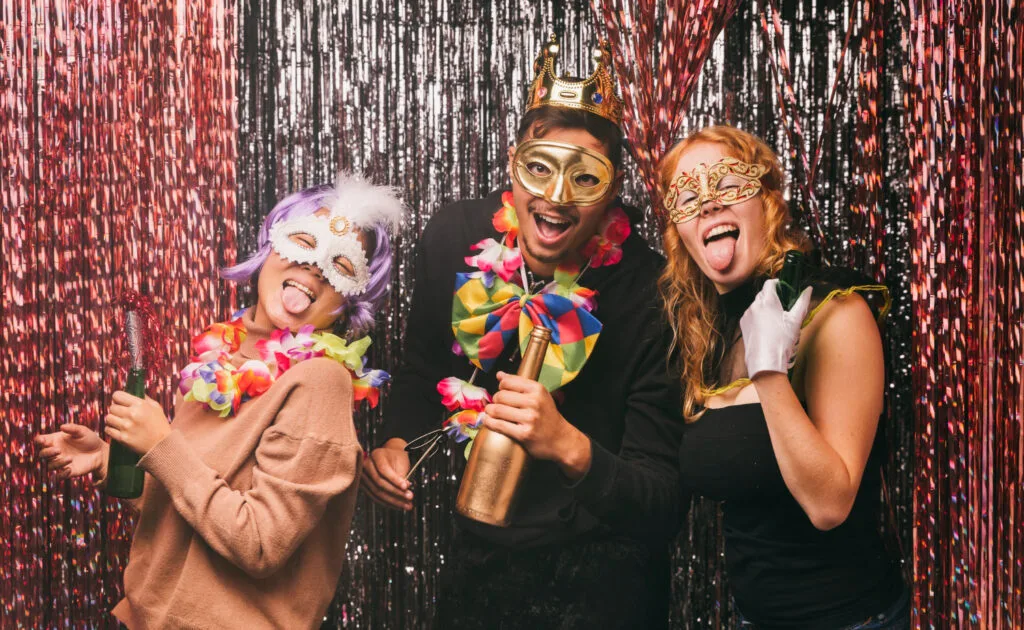 two women and a man taking pictues on a photobooth