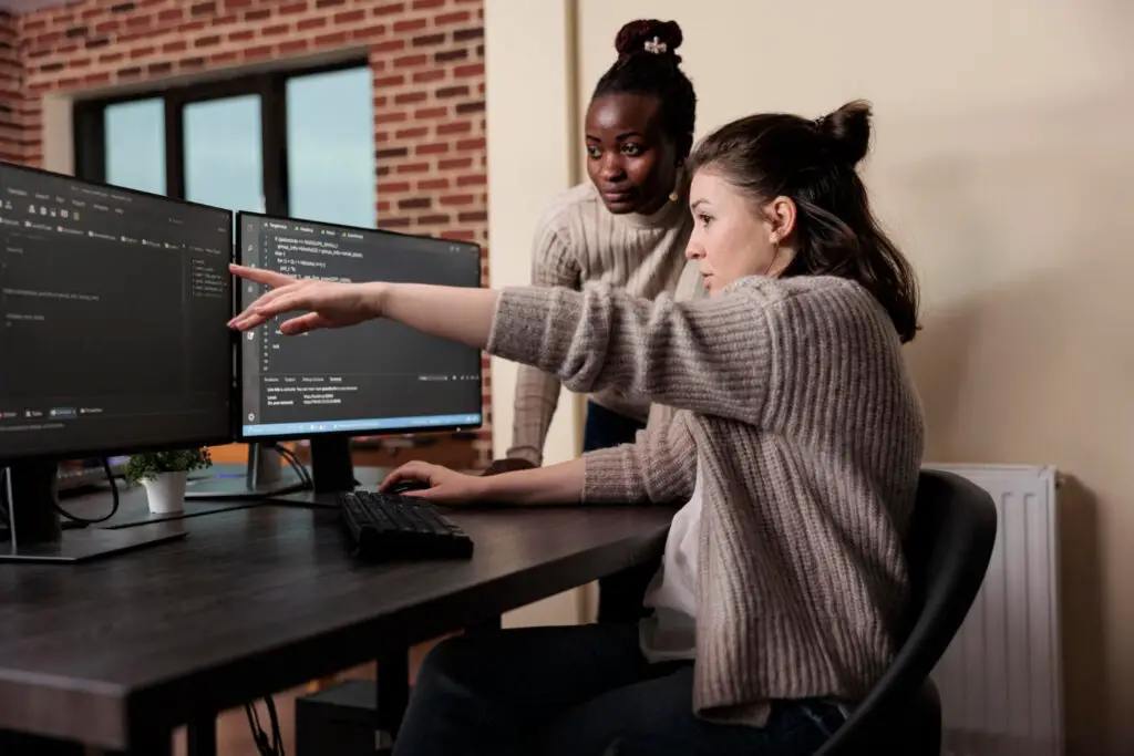 woman helping another woman in software programming