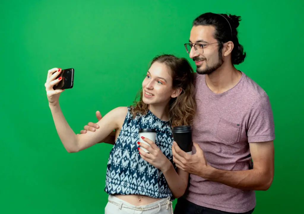 a man and a woman taking pictures on a green photobooth