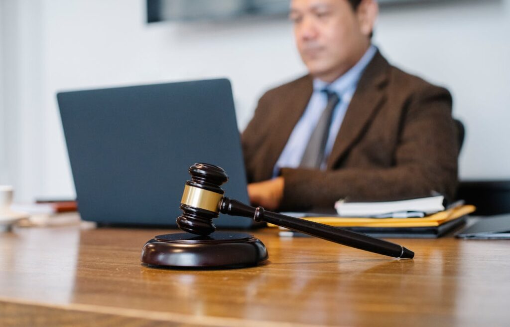 gavel on top of a table with background of man working on law firm.