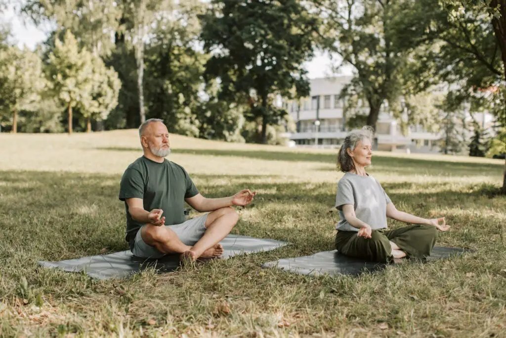 A middle-aged couple practicing yoga outdoors.