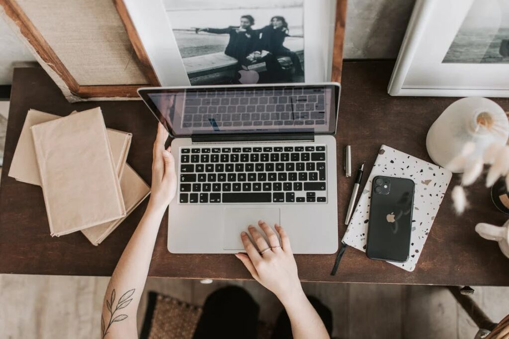 Laptop, mobile phone and picture frame on top of the table.