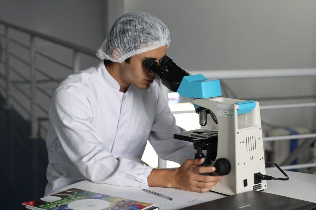 man on a white dress looking using a microscope