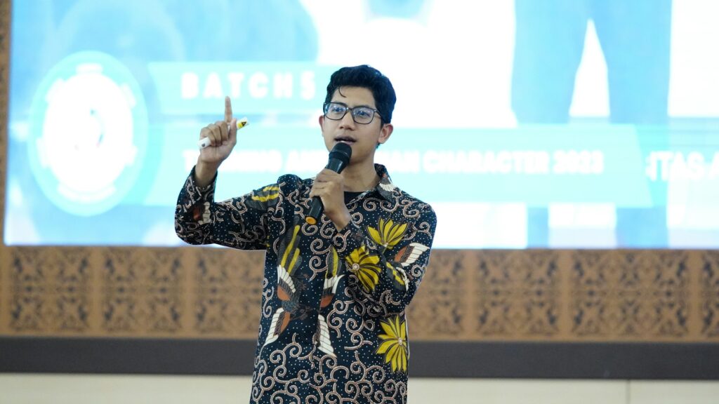 A man holding a pen while delivering a public speech.